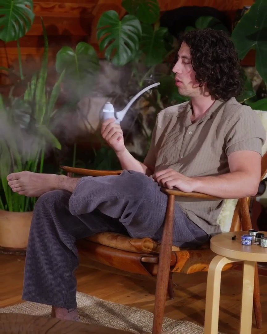 Person im Sessel mit dem Puffco Proxy Wizard, Pflanzen im Hintergrund